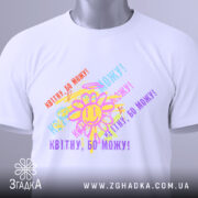 Футболка квітну бо можу, біла, зображена на плоскій поверхні, фон світло-сірий, принт з усміхненим сонечком та кольоровими написами, що повторюють фразу 'Квітну, бо можу!', з етикеткою на рукаві.