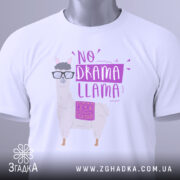 Футболка лама без драми, біла, складена на поверхні, фон світло-сірий, принт з лемуром у окулярах та написом 'NO DRAMA LLAMA' у фіолетових тонах, з етикеткою на комірці.