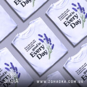 Футболка лаванда гарний настрій. Біла футболка на манекені, з принтом, що містить текст і зображення лаванди. Принт розташований зліва, текст чорного кольору, а лаванда виконана в фіолетових відтінках. Фон світло-сірий, що підкреслює яскравість кольорів.