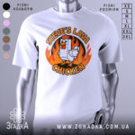 Футболка лавова курка білого кольору, зображена на манекені, ракурс спереду, фон світло-сірий, принт з куркою та вогнем у яскравих кольорах.