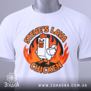 Футболка лавова курка білого кольору, складена на столі, ракурс зверху, фон світло-сірий, принт з куркою та вогнем, прикріплена етикетка зеленого кольору.