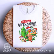 Футболка легендарний заміс, біла, складена на плетеній основі, фон білий, принт з веселими овочами та фруктами, виглядає стильно та привабливо.