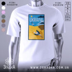 Футболка лелеки летять, біла, зображена на манекені, фон світло-сірий, принт з лелекою на жовтому полі та написом 'UKRAINE' у верхній частині.