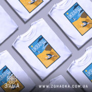 Футболка лелеки летять, біла, зображена на манекені, фон світло-сірий, принт з лелекою на жовтому полі та написом 'UKRAINE' у верхній частині.