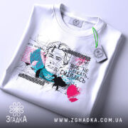 Футболка Леся емоції. Біла футболка з принтом, зображенням жінки з коротким волоссям, на фоні кольорові плями та графічні елементи. Принт містить текст українською мовою.