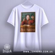 Футболка Леся Українка білого кольору, зображена на манекені, фон світло-сірий, принт з портретом жінки, яка показує жест миру, на фоні дошки з написом 'Чесний покрив не потрібен'.