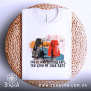 Футболка Леся Українка, білого кольору, зображена зверху на плетеній основі, фон світлий, принт містить портрет Лесі Українки з кольоровими елементами та текстом.