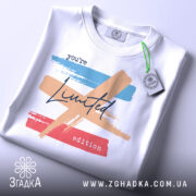 Футболка лімітована колекція, біла, зображена зверху, фон світло-сірий, принт з кольоровими мазками: блакитним, персиковим та червоним, текст 'you're Limited edition' написаний чорним шрифтом, на футболці є етикетка з зеленим шнурком.