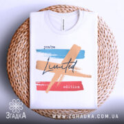 Футболка лімітована колекція, біла, зображена зверху на плетеній основі, фон світло-сірий, принт з кольоровими мазками: блакитним, персиковим та червоним, текст 'you're Limited edition' написаний чорним шрифтом.