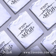 Футболка літак мрія, біла, зображена на манекені з ближнього ракурсу, фон нейтральний, принт з літаком АН-225 та написом «МРІЯ» чорного кольору.