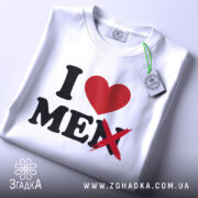 Футболка люблю себе чоловіків, біла, зображена в горизонтальному положенні, фон світло-сірий, принт з червоним сердечком і чорним текстом, де слово 'MEN' перекреслене, на комірці є етикетка.