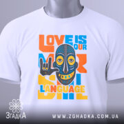 Футболка любов мова, біла, зображена зверху, фон світло-сірий, принт з написом 'LOVE IS OUR LANGUAGE' у яскравих кольорах, з малюнком маски, на футболці є етикетка з логотипом.