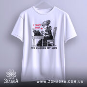 Футболка любовні історії. Біла футболка, підвішена на вішалці, з принтом дівчини за друкарською машинкою. На принті червоним написано 'I LOVE YOU', а нижче чорним 'IT'S RUINING MY LIFE'. Фон світло-сірий, футболка має короткі рукави.