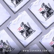 Футболка любовні історії. Біла футболка на манекені, з принтом, що зображує дівчину за друкарською машинкою. На принті червоним написано 'I LOVE YOU', а нижче чорним 'IT'S RUINING MY LIFE'. Фон світло-сірий, футболка має короткі рукави.