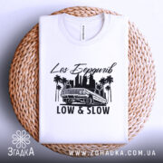 Футболка Лос Бердичів білого кольору, складена на плетеній основі, з принтом чорного кольору, що містить напис 'Los Бердичів' та малюнок автомобіля, без додаткових елементів.