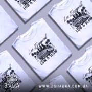 Футболка Лос Бердичів білого кольору, зображена на манекені, з принтом чорного кольору, що містить напис 'Los Бердичів' та малюнок автомобіля на фоні пальм і силуету міста.