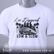 Футболка Лос Бердичів білого кольору, складена на поверхні, з принтом чорного кольору, що містить напис 'Los Бердичів' та малюнок автомобіля, з зеленим ярликом на комірці.