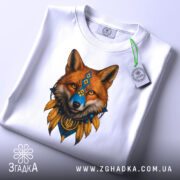 Футболка лис воїн білого кольору, складена на поверхні, ракурс зверху, фон світло-сірий, принт з лисом у національних кольорах, з етикеткою, що звисає.