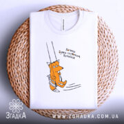 Футболка лисичка качайся, складена біла футболка на плетеній основі, принт з лисичкою на гойдалці, текст українською мовою, фон світлий.
