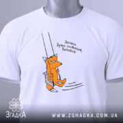 Футболка лисичка качайся, складена біла футболка на світлому фоні, принт з лисичкою на гойдалці, текст українською мовою, етикетка з зеленим шнурком.