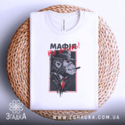 Футболка мафія не спить, складена біла футболка на плетеній основі з принтом, зображення горили в капелюсі з сигарою, червоний текст "МАФІЯ не спить!", фон світло-сірий.
