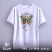 Футболка магія метелика білого кольору, підвішена на вішалці, зображена з фронтального ракурсу, фон світло-сірий, принт з метеликом в яскравих кольорах, оточений декоративними елементами.