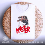 Футболка майстер планів, білого кольору, складена на плетеній кошику, фон світло-сірий, принт з рукою, що тримає ляльку, червоний текст 'MASTER' та чорний 'PLANNER'.