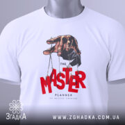 Футболка майстер планів, білого кольору, складена на поверхні, фон світло-сірий, принт з рукою, що тримає ляльку, червоний текст 'MASTER' та чорний 'PLANNER', з етикеткою зеленого кольору.