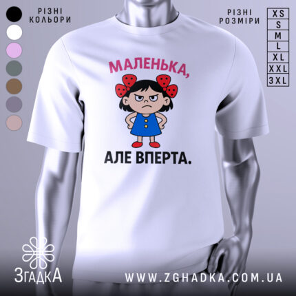 Футболка маленька вперта, білого кольору, зображена на манекені з правого ракурсу, фон світло-сірий, принт з малюнком дівчинки в блакитній сукні з червоними бантиками на волоссі та написом 'МАЛЕНЬКА, АЛЕ ВПЕРТА.'