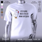 Футболка мама красеня народила, біла, зображена на манекені, фон світло-сірий, принт з качкою, що тримає келих, текст чорний.