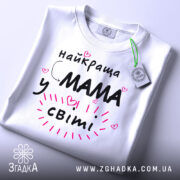 Футболка мама у світі, біла, зображена спереду на манекені, фон світло-сірий, принт чорний з рожевими елементами та сердечками, текст говорить 'найкраща мама у світі'.
