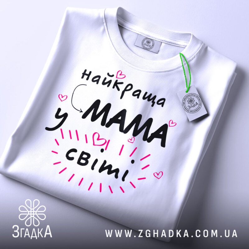 Футболка мама у світі, біла, зображена спереду на манекені, фон світло-сірий, принт чорний з рожевими елементами та сердечками, текст говорить 'найкраща мама у світі'.