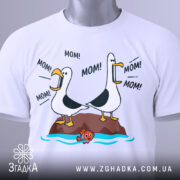 Футболка мамин день, біла, зображена з верхнього ракурсу, на фоні світло-сірого кольору, принт з двома птахами, що кричать 'MOM!', з зеленим ярликом.