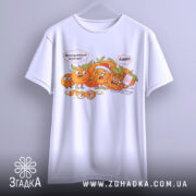 Футболка мандариновий маніяк, біла, підвішена на вішалці, з принтом мандаринів, що реагують на ситуацію, на фоні світло-сірого кольору.