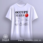 Футболка Марс колонізує біла, підвішена на вішалці, з принтом 'OCCUPY MARS' та червоною планетою, на фоні світло-сірого градієнту.