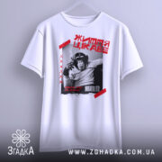 Футболка мавпа життя цікаве. Біла футболка, підвішена на фоні сірого кольору, з принтом чорного мавпи, що курить. Принт обрамлений червоними смужками та текстом.