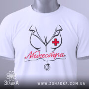 Футболка медсестра білого кольору, складена на столі, з видимим етикеткою, фон світло-сірий, принт з малюнком медсестри та написом 'Медсестра' червоного кольору.