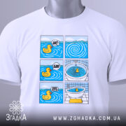 Футболка Мем Качечка, біла, лежить на столі, фон світлий, принт з шести коміксів з качечкою, яскраві кольори, на комірці є етикетка.