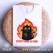 Футболка Мем Кіт білого кольору, зображена зверху на плетеній кошику, фон світло-сірий, принт з чорним котом у вогняному обрамленні, текст "EVERYTHING IS FINE!" під котом.