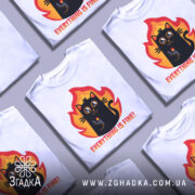 Футболка Мем Кіт білого кольору, зображена з правого ракурсу на манекені, фон світло-сірий, принт з веселим чорним котом на фоні вогню, текст "EVERYTHING IS FINE!" під котом.