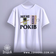 Футболка мені років. Біла футболка, підвішена на вішалці, з принтом, що містить малюнки касети та персонажа з олівцем, фон світло-сірий.