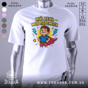 Футболка мій день перемога, біла, зображена на манекені, фон світло-сірий, принт з веселим хлопчиком у костюмі супергероя, оточеним блискавками і написом.