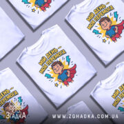 Футболка мій день перемога, біла, зображена на манекені, фон світло-сірий, принт з веселим хлопчиком у костюмі супергероя, оточеним блискавками і написом.