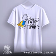 Футболка мій тато герой, біла, зображена з фронтального ракурсу, на фоні світло-сірого кольору, принт з малюнком хлопчика в жовтому плащі та текстом "Мій тато це мій герой".