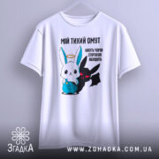 Футболка мій тихий омут. Біла футболка, підвішена на вішалці, з принтом, що зображує заєць і демон. Принт яскравий, з чіткими деталями, фон світлий, акцент на малюнку.