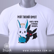 Футболка мій тихий омут. Біла футболка, складена на поверхні, з принтом, що зображує заєць і демон. Принт яскравий, з чіткими кольорами, на фоні світлого кольору. Яскравий етикет з зеленим шнурком.