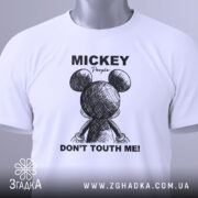 Футболка міккі маус білого кольору, зображена зверху на плоскій поверхні, фон світло-сірий, принт з малюнком міккі мауса ззаду та текстом 'DON'T TOUTH ME!' у чорному кольорі, на футболці є етикетка з зеленим шнурком.