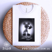 Футболка міккі повертається, біла, складена на плетеному кошику, фон світло-сірий, принт з силуетом міккі мауса з піднятою рукою та написом "I WILL BE BACK...".