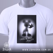 Футболка міккі повертається, біла, складена на столі, фон світло-сірий, принт з силуетом міккі мауса з піднятою рукою та написом "I WILL BE BACK...", на футболці є етикетка з зеленим шнурком.