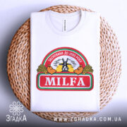 Футболка мілфа заснована білого кольору, зображена в складеному вигляді на плетеній основі, фон світлий, принт містить текст 'MILFA' та малюнок вітряка, видима етикетка на комірці.